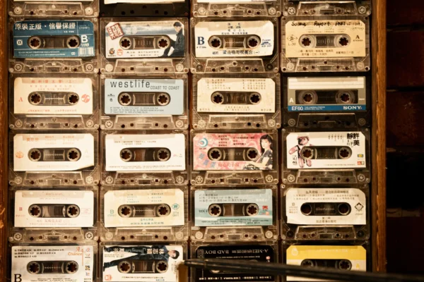 Collection of vintage cassette tapes organized in wooden shelving unit with Asian text labels and various record labels visible.