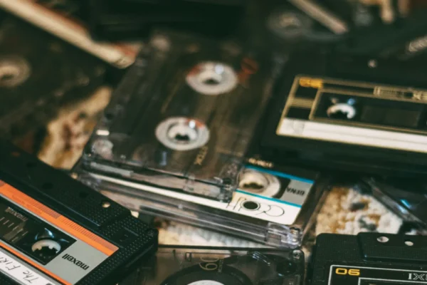 Collection of vintage cassette tapes with orange and black labels scattered on a textured surface.